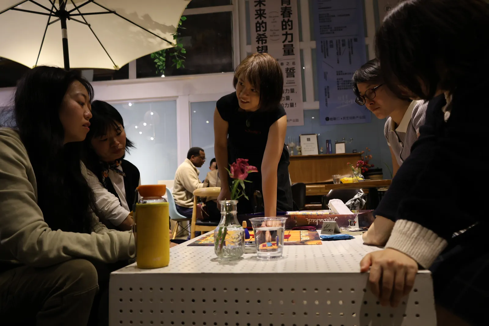 Someone standing to explain the rules of a game to four seated players