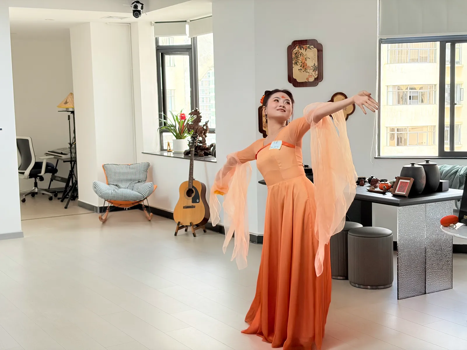 A dancer mid-move in a flowing orange gown, sleeves thrown out