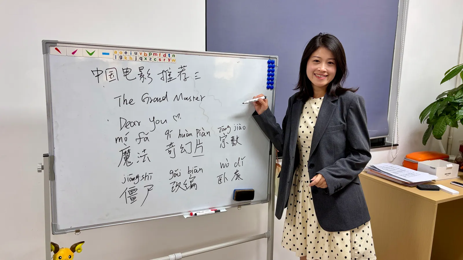 A host at the whiteboard with the day’s vocabulary and a Chinese film to watch