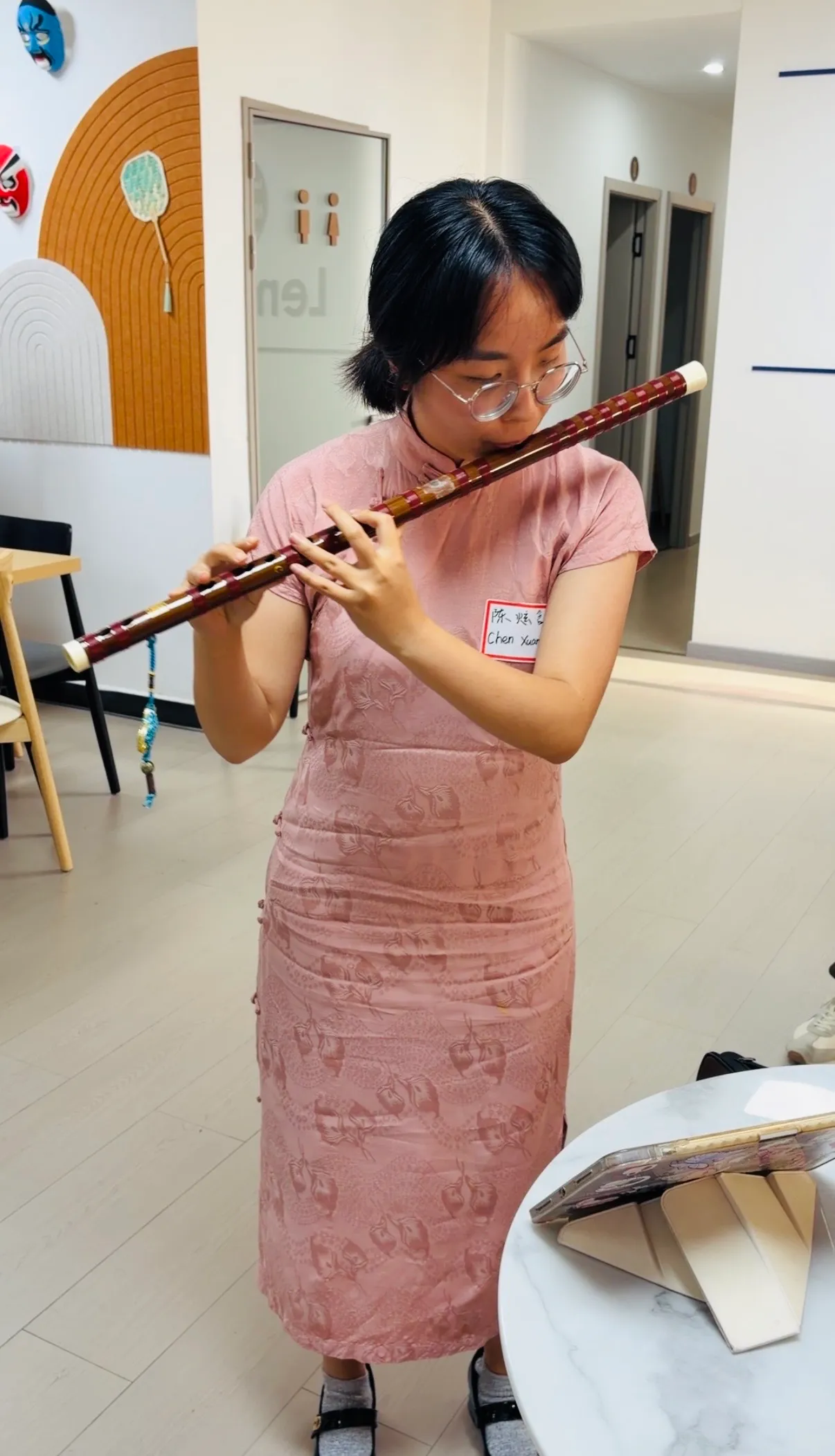 Someone in a qipao playing a Chinese musical instrument for the room