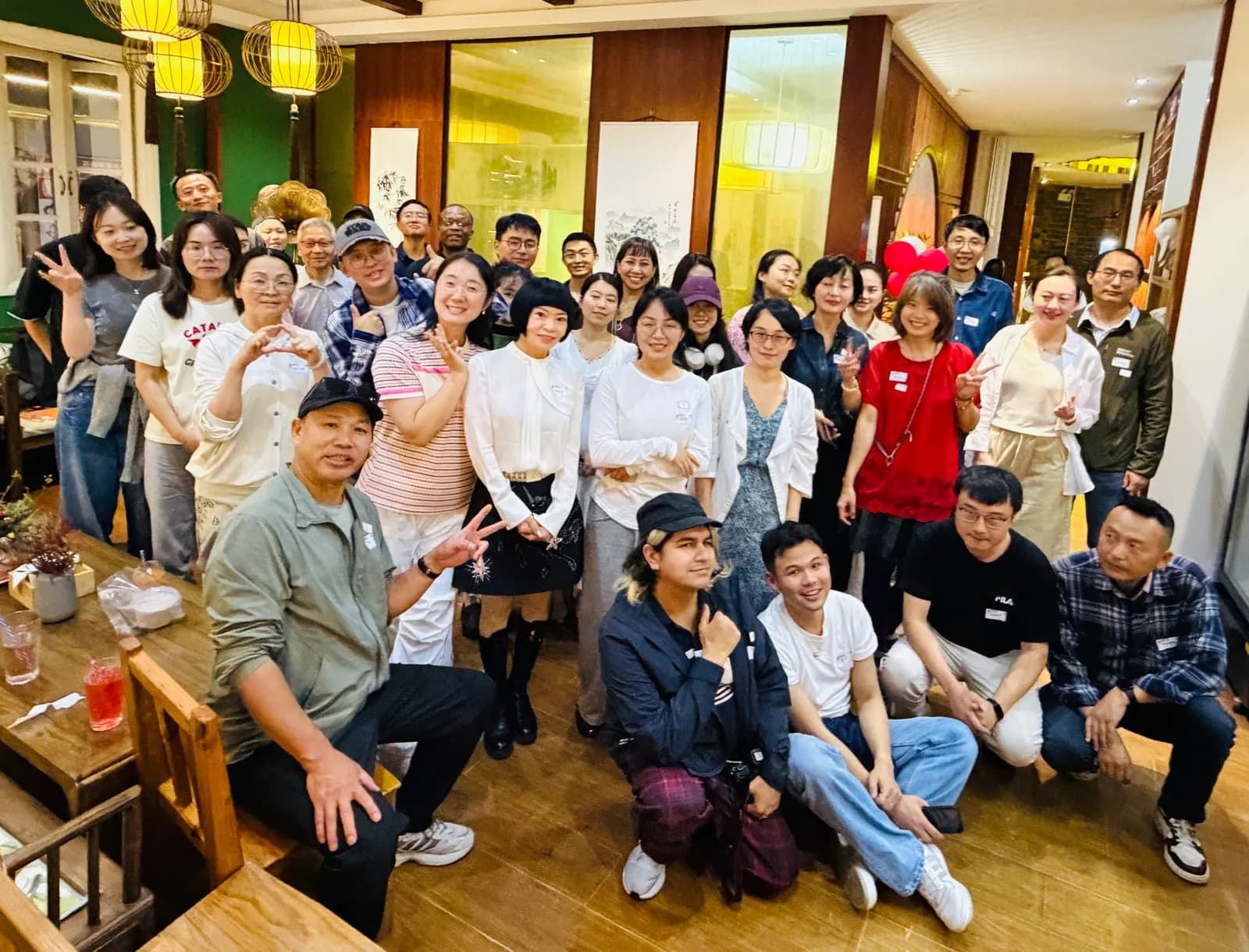 The whole room packed together for a group photo under the lanterns