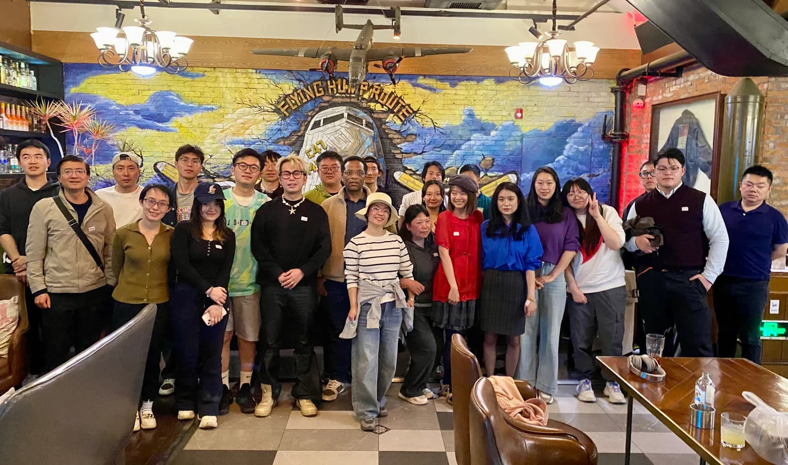 A group photo in front of the Flying Hump Route mural at the bar